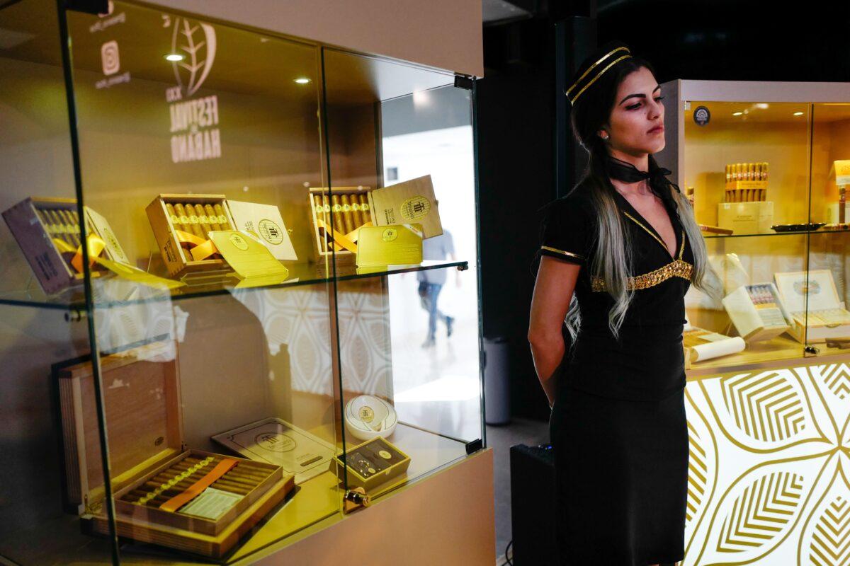 A Cuban model stands next to a display with varieties of cigars, during the opening of the 22nd Cigar Festival, at the Havana Convention Center, Cuba, on Feb. 24, 2020. (Adalberto Roque/AFP via Getty Images)