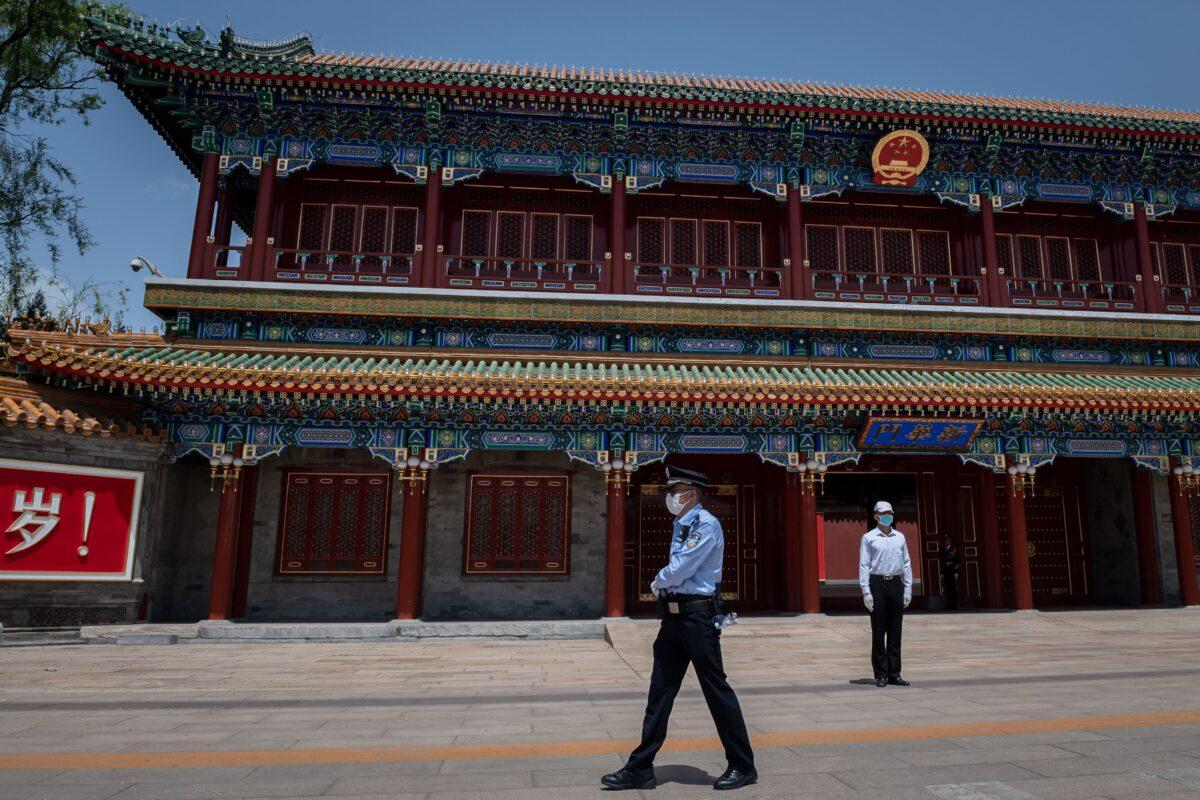 A security guard (R) and a police officer (L) secure the area at the entrance to the Zhongnanhai leadership compound in Beijing on May 18, 2020. (Nicolas Asfouri/AFP via Getty Images)