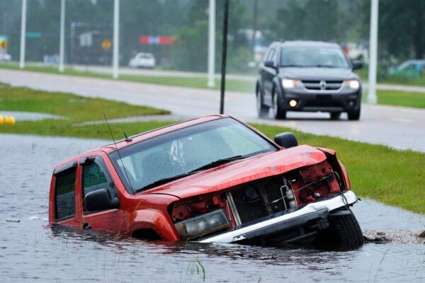An abandoned vehicle is half-submerged in a ditch next to a near-flooded highway as the outer bands of Hurricane Ida arrive in Bay Saint Louis, Miss., on Aug. 29, 2021. (Steve Helber/AP Photo)