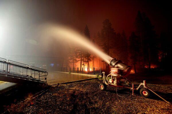 A snowmaking machine blasts water as the Caldor Fire burns at Sierra-at-Tahoe ski resort in Eldorado National Forest, Calif., on Aug. 30, 2021. (Noah Berger/AP Photo)