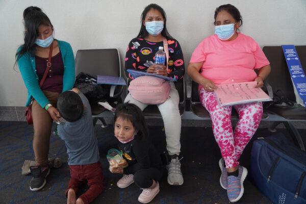 An unknown illegal immigrant (left), Selena (center), and Melanie (right) wait for their first airline flight along with their children in the McAllen, Texas, airport on Aug. 28, 2021. (Jackson Elliott/The Epoch Times)