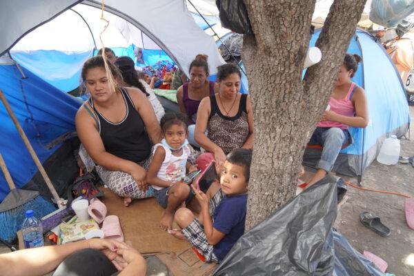Two families wait outside their adjacent tents in the Reynosa, Mexico refugee camp on Aug. 28, 2021. (Jackson Elliott/The Epoch Times)