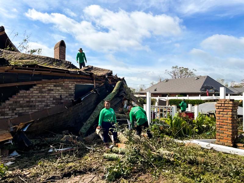 Celestina Greco (C) works with her crew to remove a tree from a house after Hurricane Ida swept through, in St John Parish, La., on Aug. 31, 2021. (Charlotte Cuthbertson/The Epoch Times)