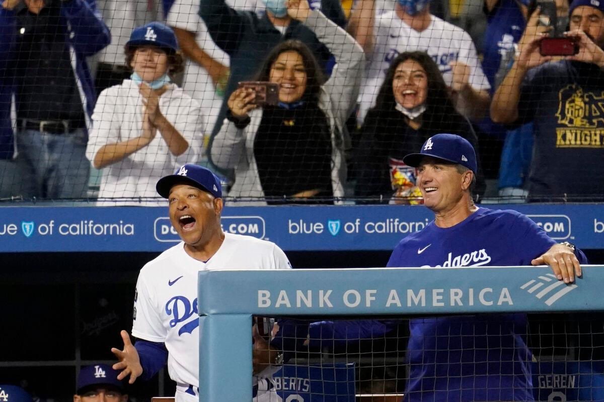 Los Angeles Dodgers manager Dave Roberts, left, and bench coach Bob Geren react after a solo home run by Mookie Betts during the third inning of a baseball game against the Atlanta Braves in Los Angeles on Aug. 30, 2021. (AP Photo/Marcio Jose Sanchez)