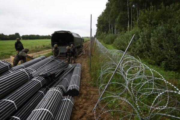 Polish soldiers unload materials to construct a barbed wire fence on the border with Belarus in Zubrzyca Wielka near Bialystok, eastern Poland on Aug. 26, 2021. (Jaap Arriens/AFP via Getty Images)