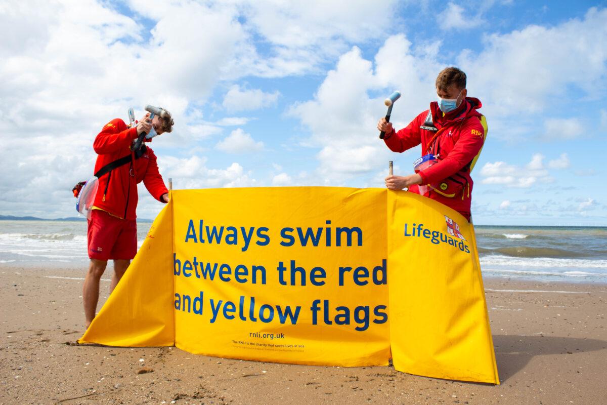 RNLI lifeguards hammer the poles of a banner on a beach in this undated handout photo. (RNLI/Callum Robinson)