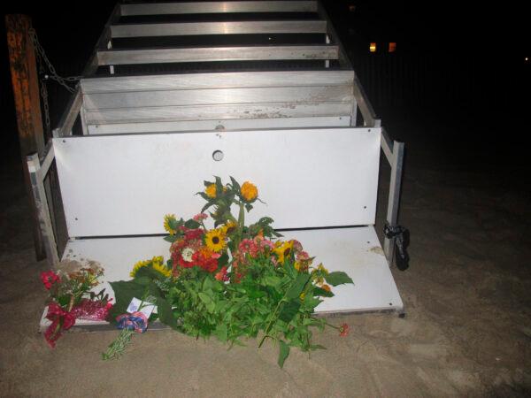 Flowers sit at the edge of an overturned lifeguard stand on the sand at the beach where a young lifeguard was killed and seven others injured by a lightning strike in Berkeley Township, N.J., on Aug. 30, 2021. (Wayne Parry/AP Photo)