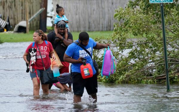Michael Thomas, back, carries his daughter Mikala, out of his flooded neighborhood after Hurricane Ida moved through in LaPlace, La., on Aug. 30, 2021. (Steve Helber/AP Photo)