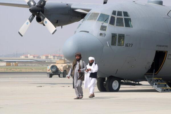 Taliban terrorists walk in front of a military airplane a day after the U.S. troop withdrawal from Hamid Karzai International Airport in Kabul, Afghanistan, on Aug. 31, 2021. (Stringer/Reuters)