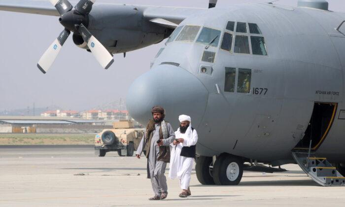 Taliban terrorists walk in front of a military plane a day after the U.S. troop withdrawal from Hamid Karzai International Airport in Kabul, Afghanistan, on Aug. 31, 2021. (Stringer/Reuters)