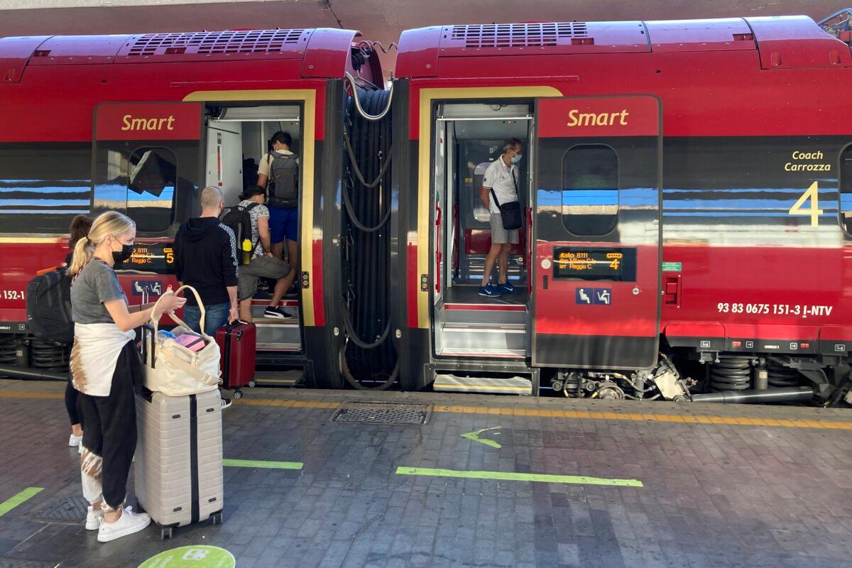 Passengers, including American tourist Riley Smith (L), board a high-speed train to to Rome, Naples, and Reggio Calabria in southern Italy from Florence's Santa Maria Novella train station, Italy, on Sept. 1, 2021. (Karl Ritter/AP Photo)