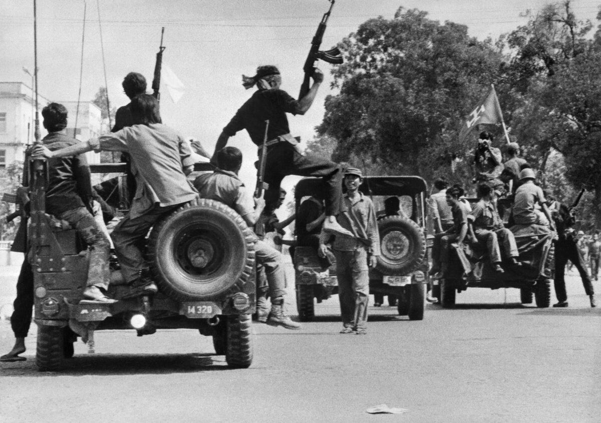 The Khmer Rouge guerilla soldiers drive jeeps through a street of Phnom Penh on April 17, 1975. The Cambodian capital surrendered after a three-and-a-half-month siege of Pol Pot forces. (Sjoberg/AFP via Getty Images)