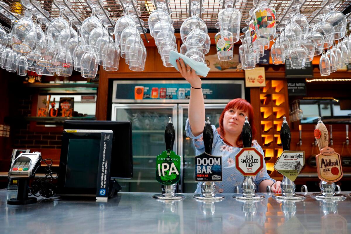 A member of staff at a Wetherspoons pub in north London cleans glasses in preparation for pubs to reopen early next month on June 24, 2020. (Tolga Akmen/AFP via Getty Images)