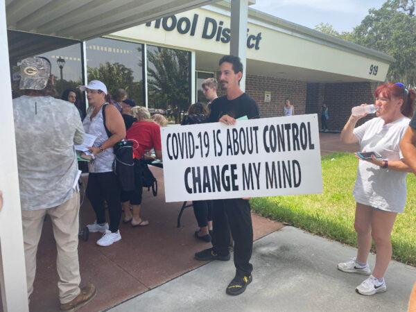 Robert Christiansen holds a sign as he waits to attend the emergency school board meeting regarding a proposed mask mandate for students in Hernando County, Fla., on Aug. 31, 2021. (Patricia Tolson/The Epoch Times)