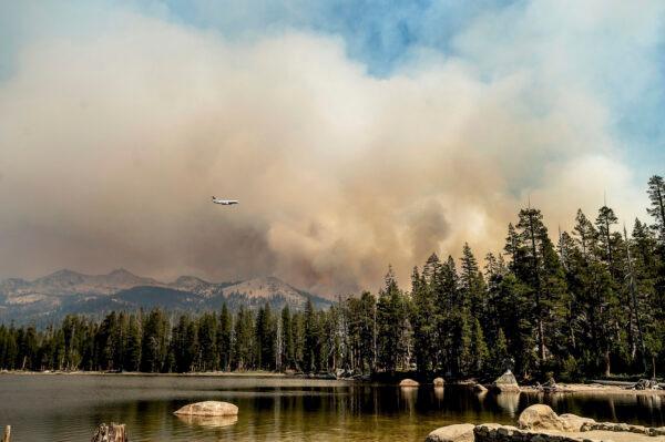 A tanker flies over Wrights Lake while battling the Caldor Fire in Eldorado National Forest, Calif., on Sept. 1, 2021. (AP Photo/Noah Berger)