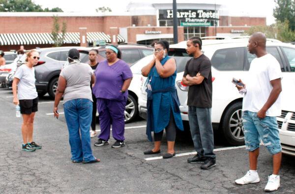 Anxious parents stand in the parking lot of a shopping center in Winston-Salem, North Carolina, on Sept. 1, 2021. (AP Photo/Skip Foreman)