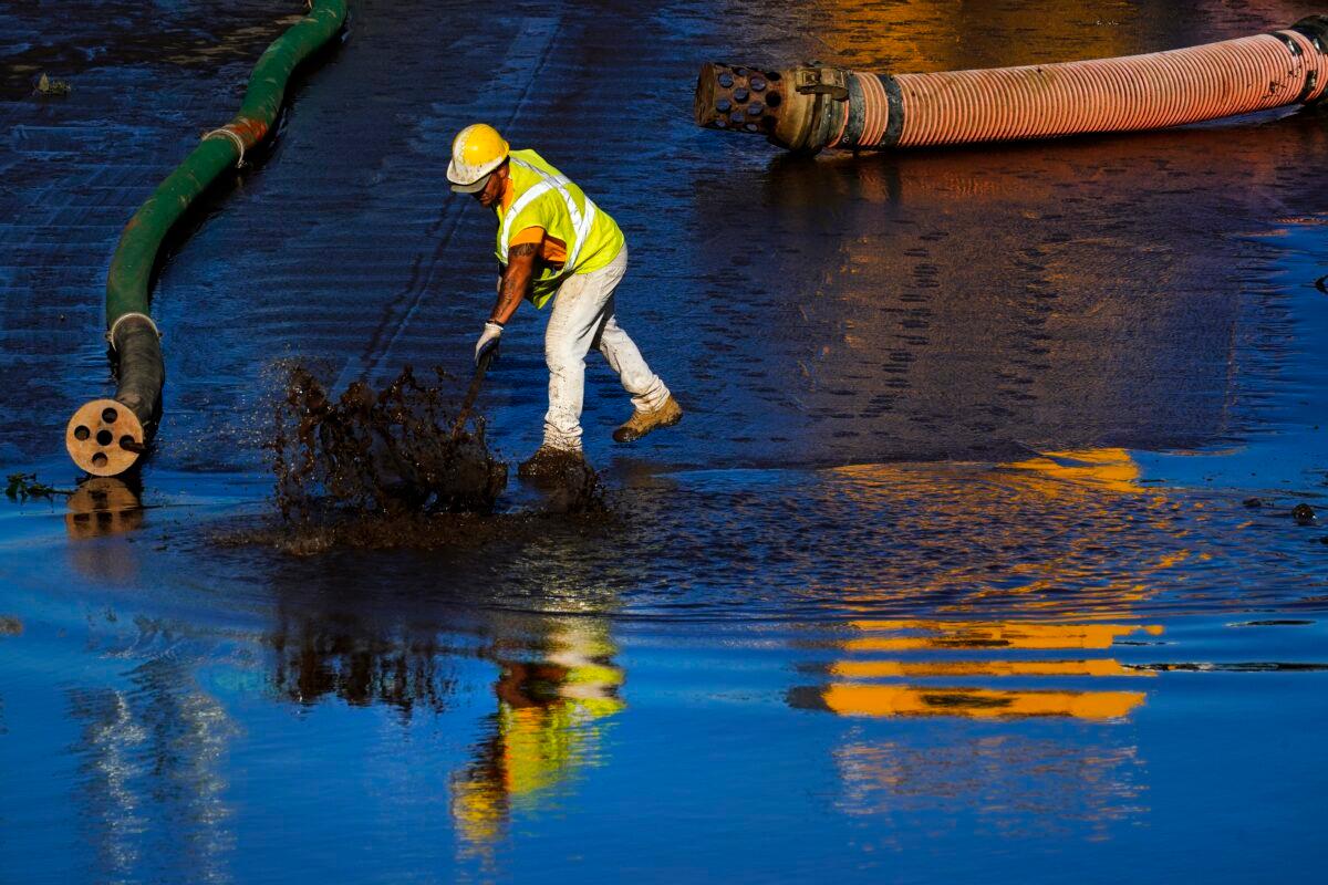 A worker scrapes sediment from a flooded section of Interstate 676 in Philadelphia, on Sept. 3, 2021. (Matt Rourke/AP Photo)