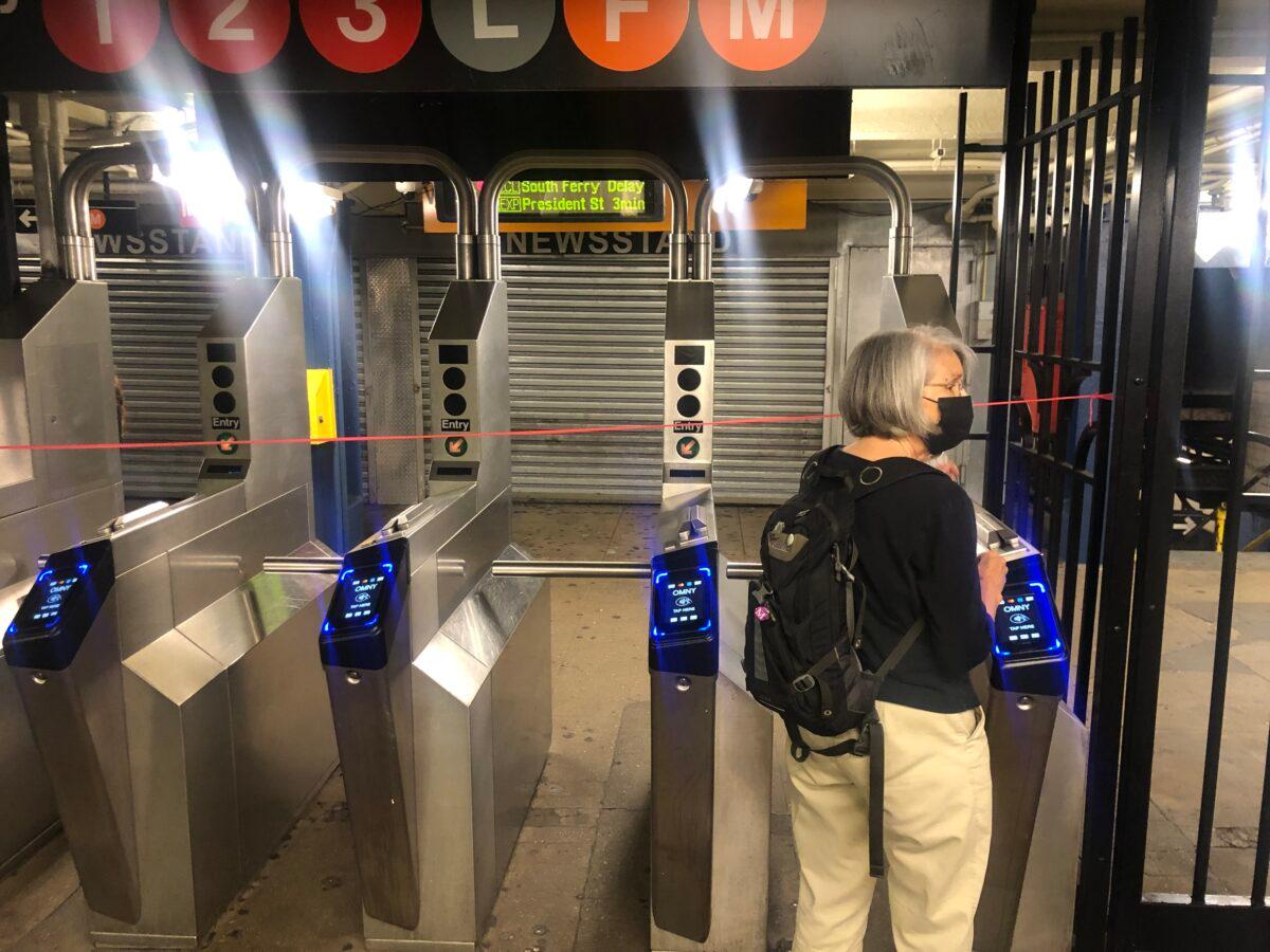 A woman notices she can't go through the turnstile at the 14th Street subway station, Manhattan, New York, on Sept. 2, 2021. (Enrico Trigoso/The Epoch Times)