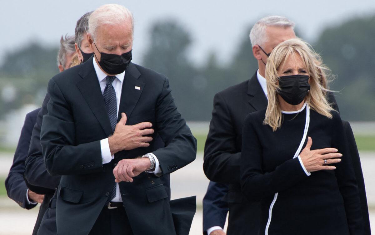 President Joe Biden, left, looks at his watch as he and First Lady Jill Biden attend the dignified transfer of the remains of fallen service members at Dover Air Force Base in Dover, Del., on Aug. 29, 2021. (Saul Loeb/AFP via Getty Images)