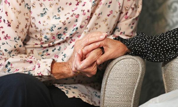 A care home resident holding hands with her daughter on Oct. 29, 2021. (Andrew Matthews/PA)