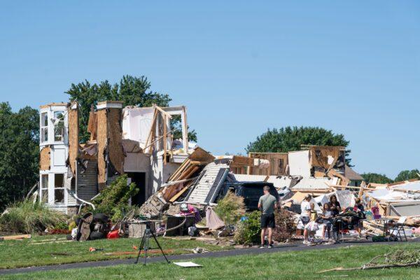 People stand by a home damaged by a tornado in Mullica Hill, N.J., on Sept. 2, 2021. (Branden Eastwood/AFP via Getty Images)