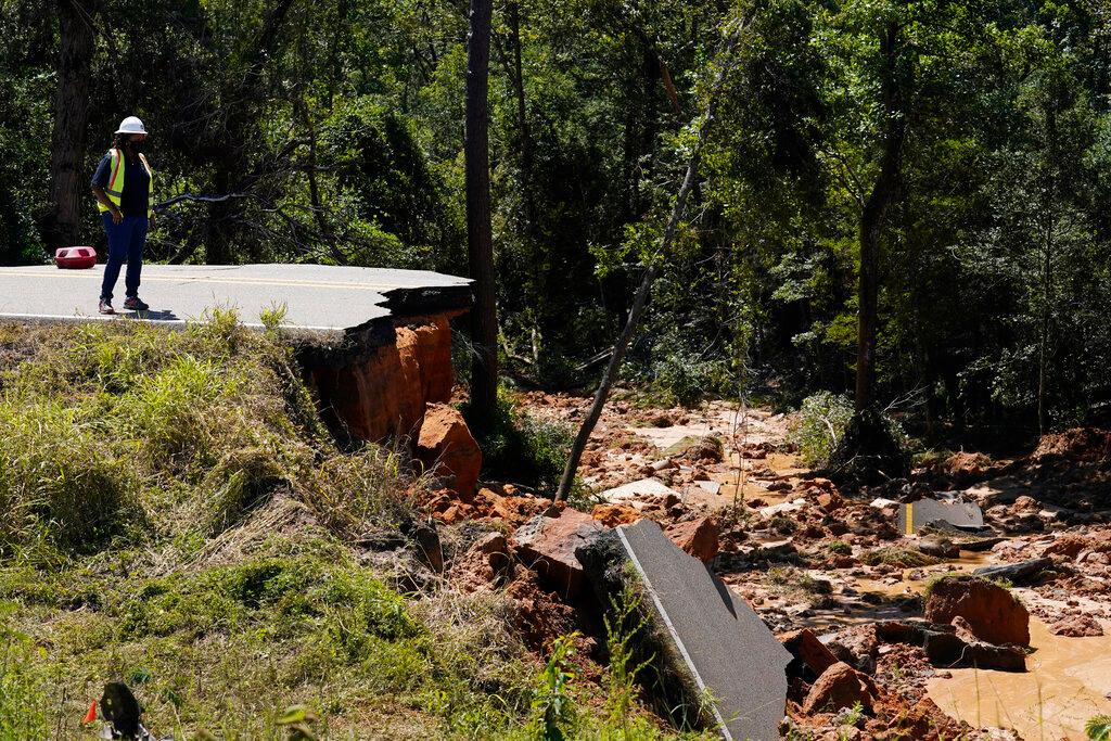 An official looks at the deep hole on Mississippi Highway 26 in the Crossroads community, on Tuesday, Aug. 31, 2021. (AP Photo/Rogelio V. Solis)