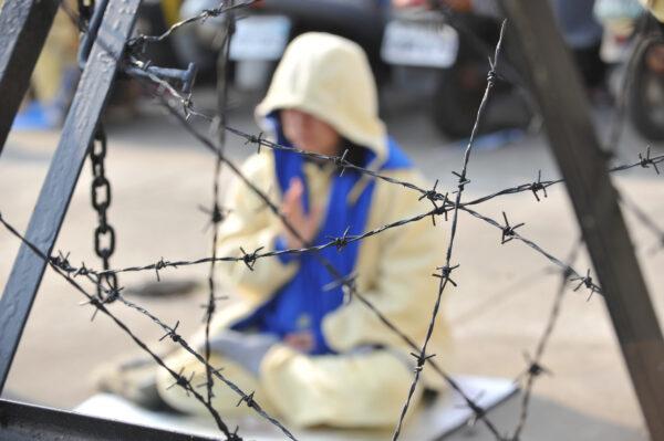 A Falun Gong practitioner sits behind the barricades during a demonstration in central Taiwan on Dec. 22, 2009. (Sam Yeh/AFP via Getty Images)