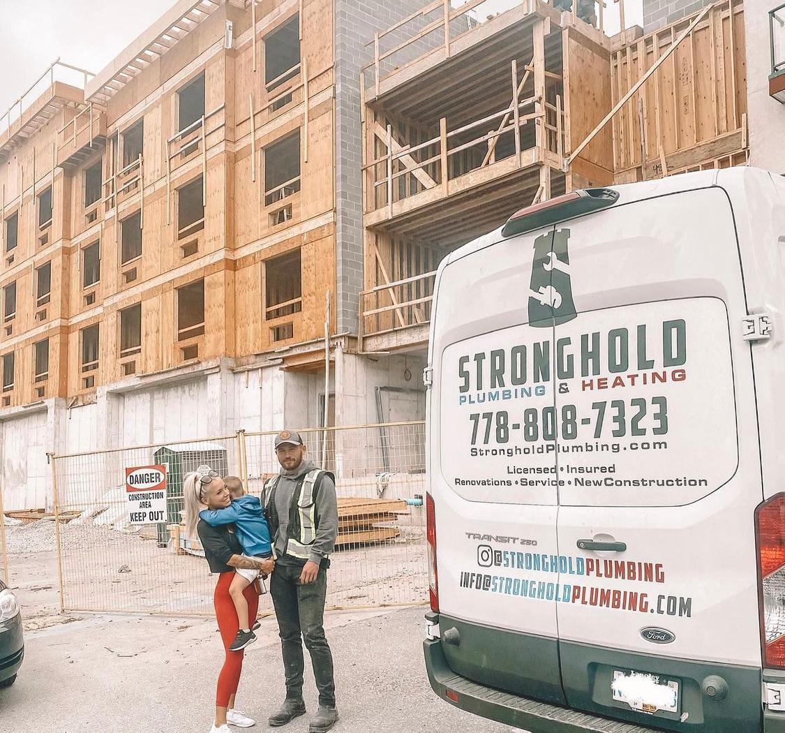 Noah Fladager with his wife, Caitlin, and son, in front of a new hotel where his company is handling the plumbing work in 40 rooms. (Courtesy of <a href="https://www.instagram.com/caitlinfladager/">Caitlin Fladager</a>)