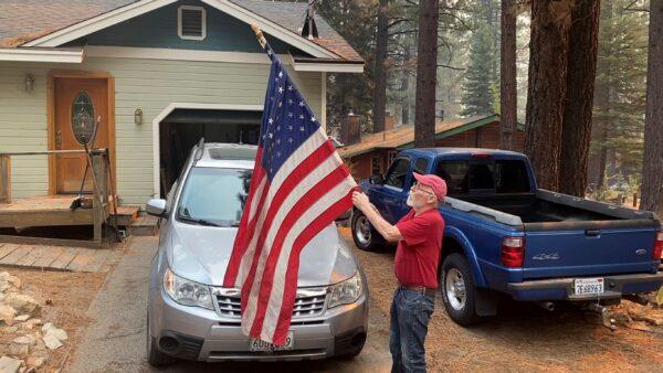 Bill Roberts rolls up an American flag in front of his house in South Lake Tahoe, Calif., a day after the city was ordered to evacuate because of the approaching Caldor Fire, Calif., on Aug. 31, 2021. (Terry Chea/AP Photo)