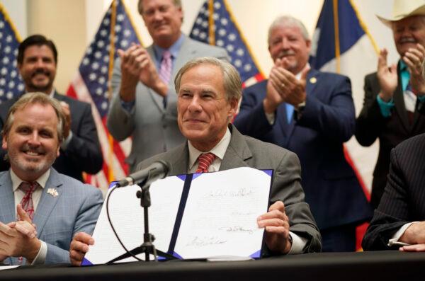 Texas Gov Greg Abbott shows off Senate Bill 1, also known as the election integrity bill, after he signed it into law in Tyler, Texas, on Sept. 7, 2021. (LM Otero/AP Photo)