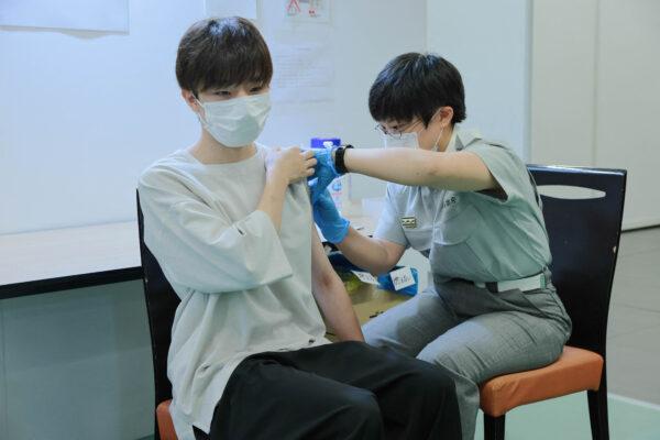 A Tokyo fire brigade staff member (R) administers a dose of the COVID-19 coronavirus vaccine at Aoyama University in Tokyo on Aug. 2, 2021. (Stanislav Kogiku/POOL/AFP via Getty Images)