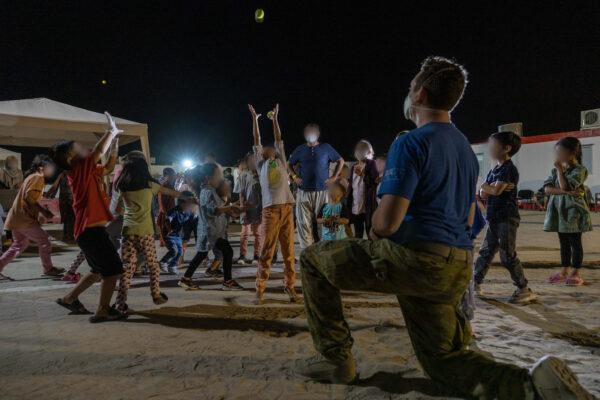 Private Ethan Wright, from 1st Battalion Royal Australian Regiment, plays with Afghanistan evacuees at a temporary camp in Australia’s main operating base in the Middle East. (LACW Jacqueline Forrester/ADF)