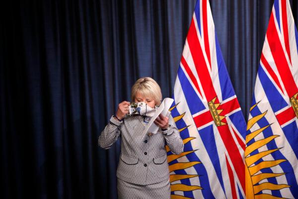 B.C. Provincial Health Officer Dr. Bonnie Henry puts on her mask following discussion of details about the province's COVID-19 vaccine card at a press conference in Victoria on Aug. 23, 2021. (The Canadian Press/Chad Hipolito)