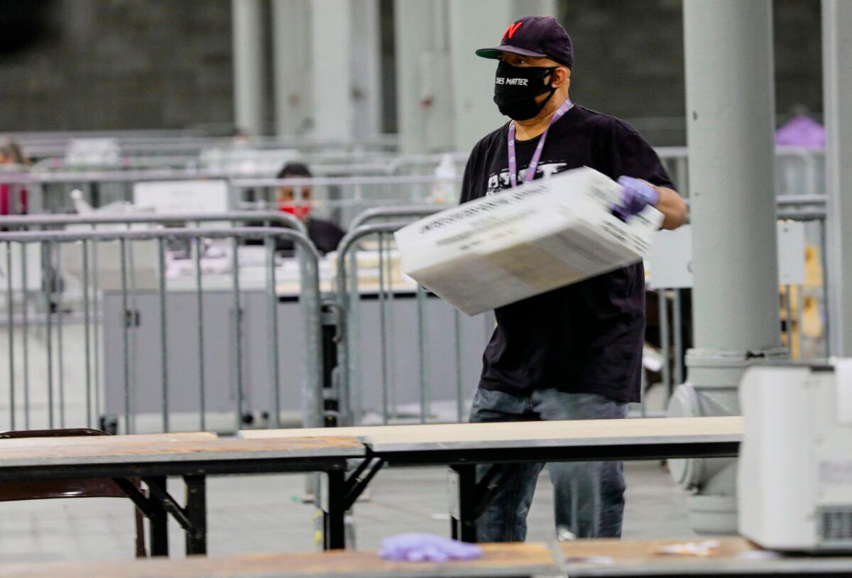 During the Georgia Senate runoff elections a worker carries a bin of ballots to be scanned at the Georgia World Congress Center in Atlanta, Ga., on Jan. 5, 2021. (Sandy Huffaker/AFP via Getty Images)