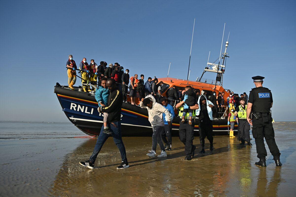 Illegal immigrants are escorted to be processed after being picked up by an RNLI (Royal National Lifeboat Institution) lifeboat while crossing the English Channel at a beach in Dungeness, southeast England, on Sept. 7, 2021. (Ben Stansall/AFP via Getty Images)