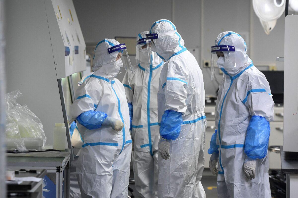 Laboratory technicians wearing personal protective equipment (PPE) working on samples to be tested for the Covid-19 coronavirus at the Fire Eye laboratory, a Covid-19 testing facility, in Wuhan in China's central Hubei province on Aug. 4, 2021. (STR/AFP via Getty Images)