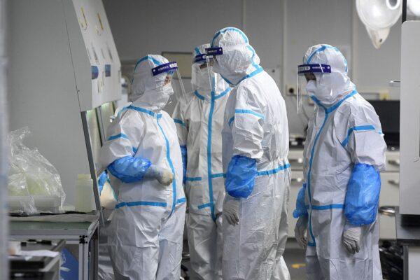 Laboratory technicians wearing personal protective equipment working on samples to be tested for COVID-19 at the Fire Eye laboratory, a COVID-19 testing facility, in Wuhan in China's central Hubei province, on Aug. 4, 2021. (STR/AFP via Getty Images)
