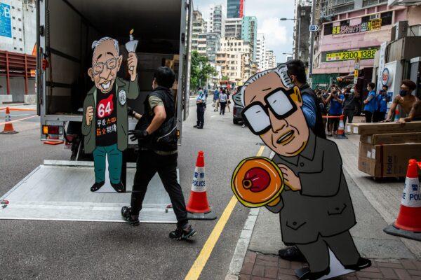 Police officers from the National Security Department take away exhibits featuring images of former Chinese Communist Party leader Zhao Ziyang (R) and pro-democracy activist Szeto Wah (L), after raiding the June 4 museum dedicated to the 1989 Tiananmen Square crackdown, in Hong Kong, on Sept. 9, 2021. (Isaac Lawrence/AFP via Getty Images)