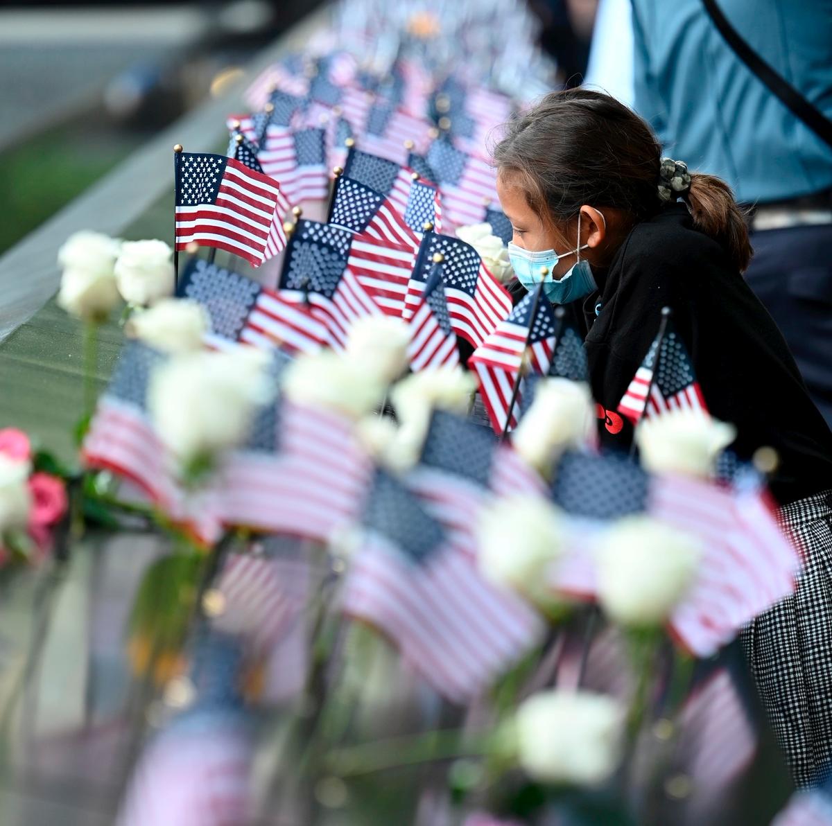 A family member at the reflecting pool places a flag during a ceremony at the National September 11 Memorial & Museum commemorating the 20th anniversary of the Sept. 11 terror attacks, in New York on Sept. 11, 2021. (David Handschuh-Pool/Getty Images)
