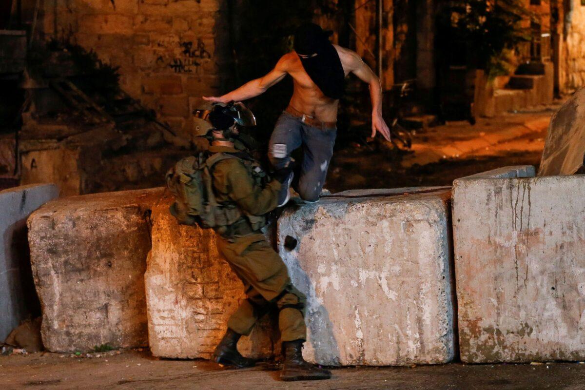 A member of the Israeli forces clashes with a demonstrator during a protest in solidarity with prisoners following the escape of six Palestinian terrorists from an Israeli prison, in Hebron in the Israeli-occupied West Bank on Sept. 9, 2021. (Mussa Qawasma/Reuters)