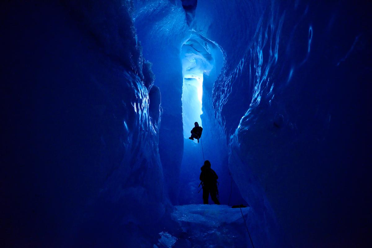The crew climbing down into the blue abyss of the ice cave. (Courtesy of Caters News)