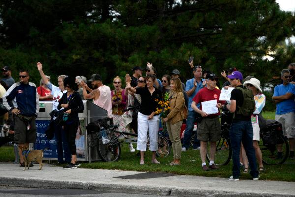 People wave as a car honks during a protest against mandatory COVID-19 vaccinations and health measures, outside the Ottawa Hospital Civic Campus in Ottawa on Sept. 13, 2021. (The Canadian Press/Justin Tang)
