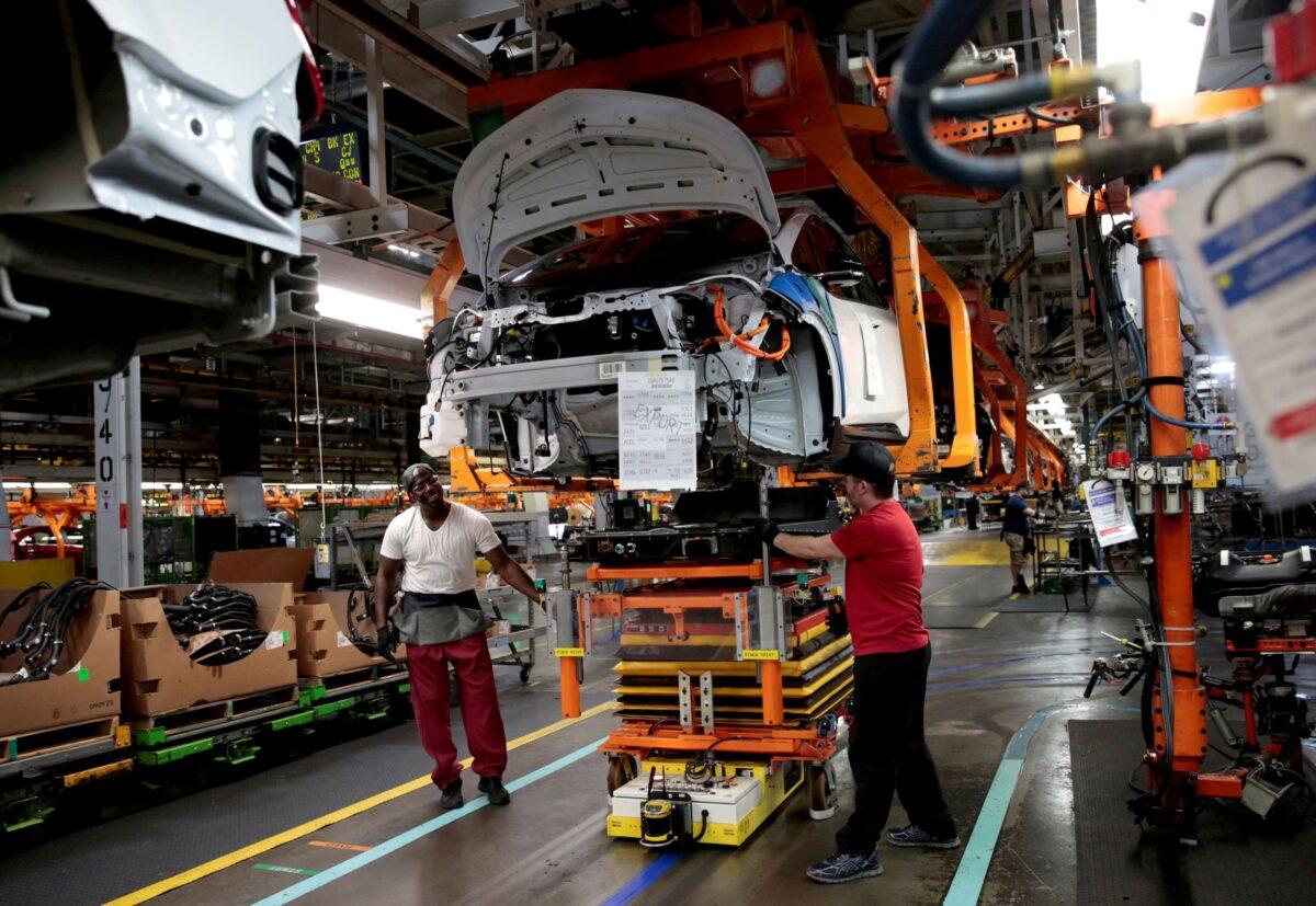 General Motors assembly workers connect a battery pack underneath a partially assembled 2018 Chevrolet Bolt EV vehicle on the assembly line at Orion Assembly in Lake Orion, Mich., on March 19, 2018. (Rebecca Cook/Reuters)
