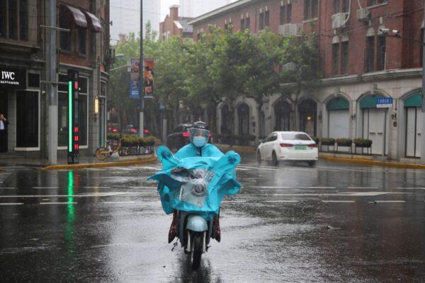 A resident rides on the street as it rains in Shanghai, China, on Sept. 13, 2021. (Chen Si/AP Photo)