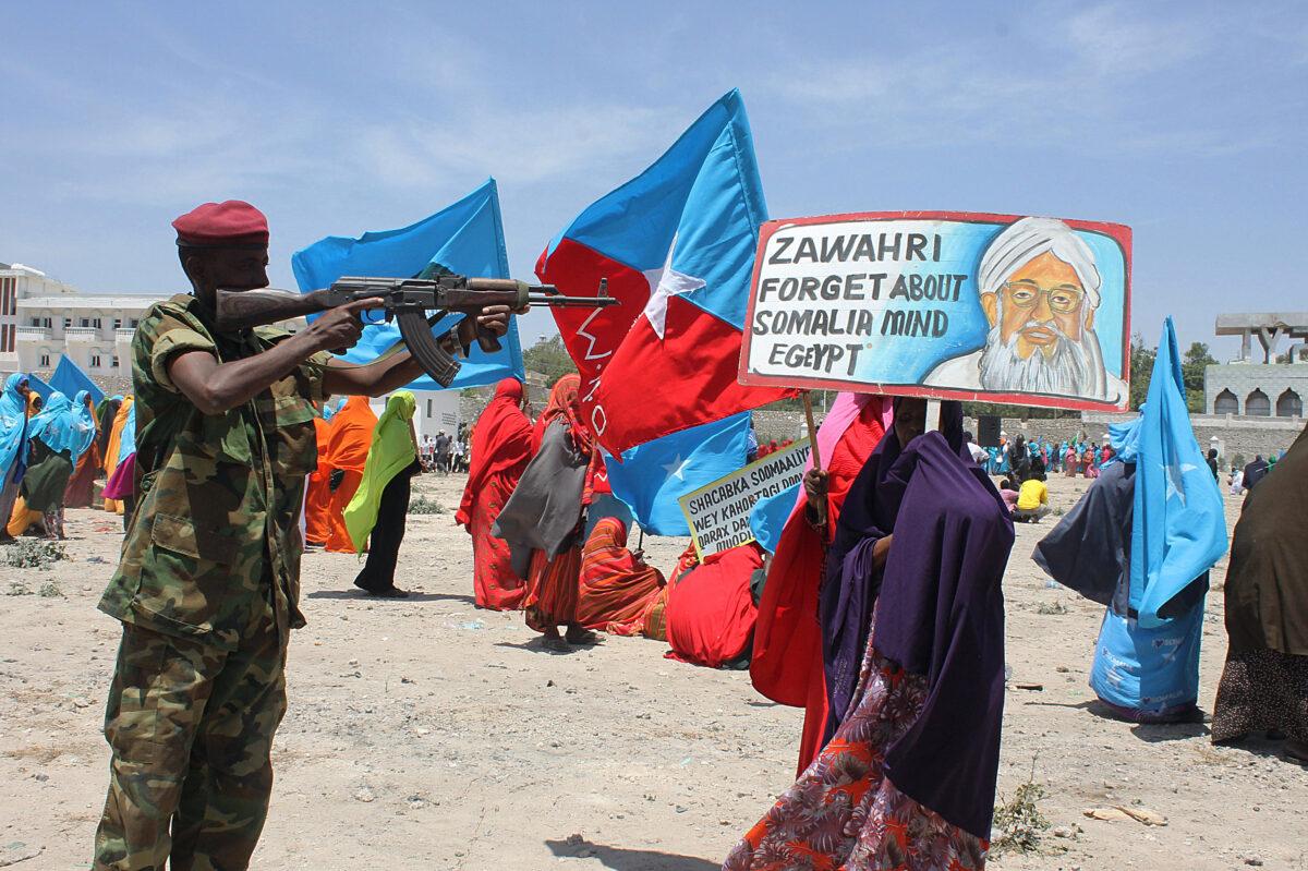 A Somali security soldier points his weapon at a poster bearing a photo of al-Qaeda leader Ayman al-Zawahiri during an anti-al-Shabab rally in Mogadishu, Somalia, on Feb. 23, 2014. (Abdifitah Hashi Nor/AFP via Getty Images)