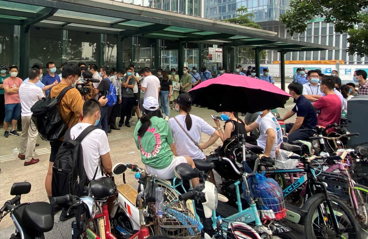 People gather to demand repayment of loans and financial products as security personnel guards outside Evergrande's headquarters in Shenzhen, Guangdong Province, China on Sept. 15, 2021. (David Kirton/Reuters)