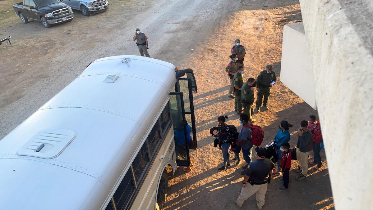 Illegal immigrants board a bus to be transported to a Border Patrol station for processing, under the international bridge, in Del Rio, Texas, on Sept. 16, 2021. (Charlotte Cuthbertson/The Epoch Times)