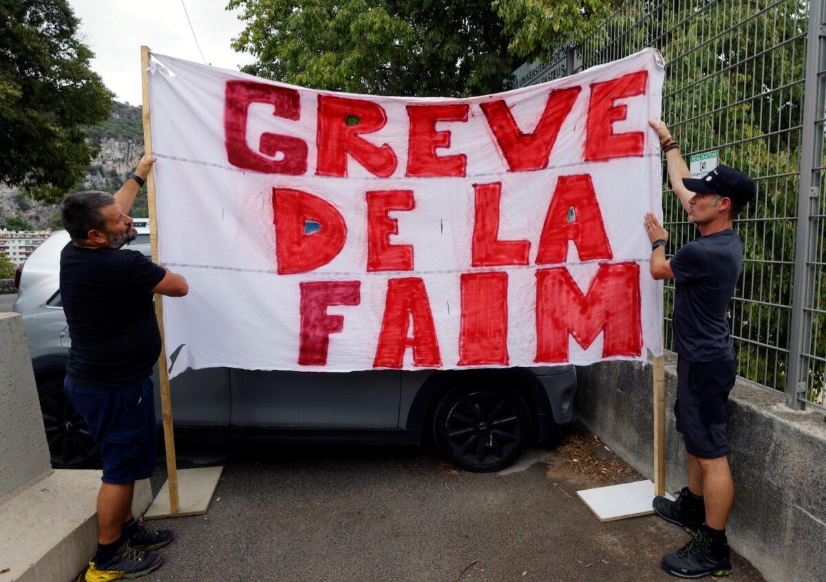 Thierry Paysant, security worker and firefighter at the Pasteur hospital, and Christophe, caregiver at the Pasteur hospital, hold a banner that reads "Hunger strike" to protest against France's restrictions, including compulsory COVID-19 passes, near the Abbaye Saint-Pons in Nice, France, on Sept. 15, 2021. (Eric Gaillard/Reuters)