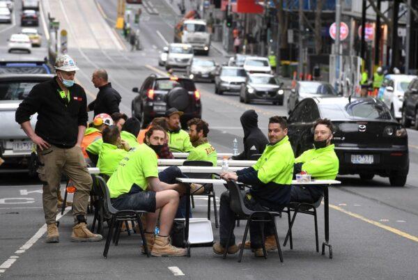 Construction workers take their lunch break on a busy street in Melbourne, Australia, to protest the closing of their onsite tea rooms by the Victorian state government, on Sept. 17, 2021. (William West/AFP via Getty Images)
