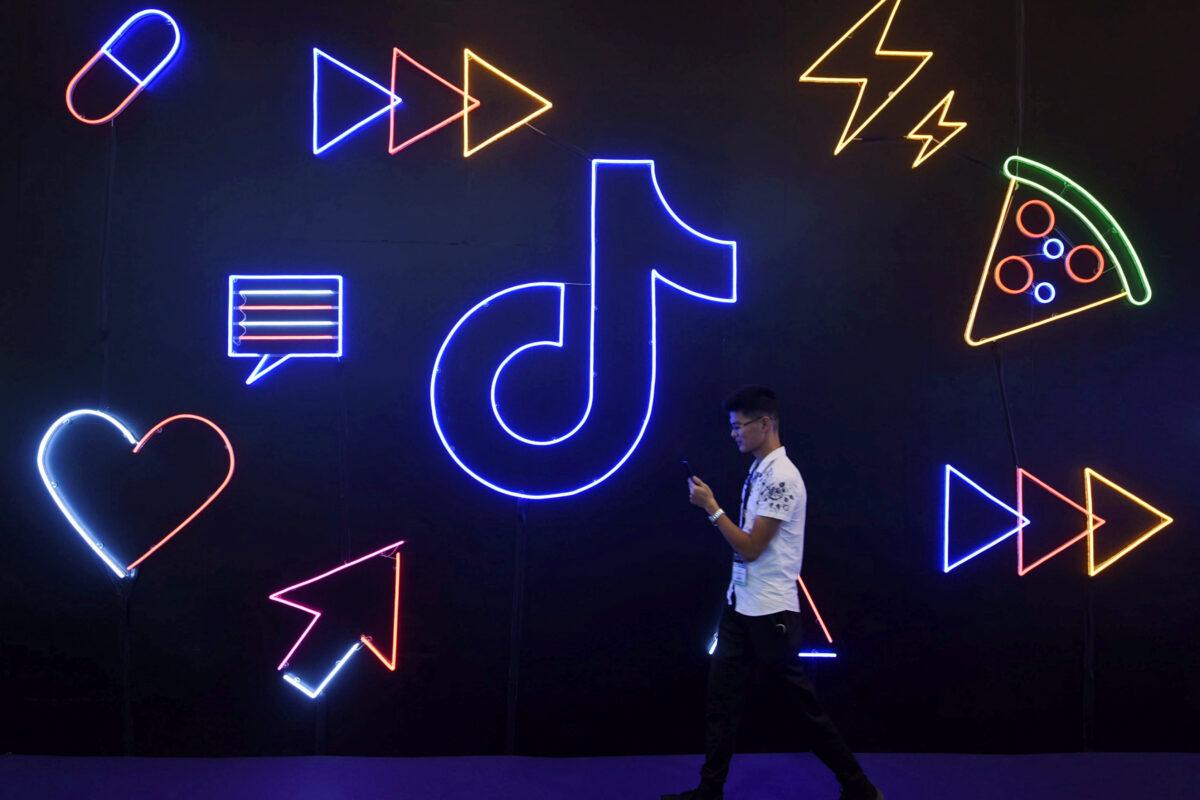 A man holding a phone walks past a sign of Chinese company ByteDance's app TikTok, known locally as Douyin, at the International Artificial Products Expo in Hangzhou, Zhejiang Province, China, on Oct. 18, 2019. (STR/Files/Reuters)